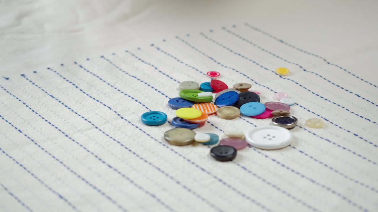 다채로운 버튼이 줄무 천에 떨어지는 클로즈업. 옷을 는 것과 전문적인 바느질 개념. 재료에 대한 버튼 액세서리를 선택하는 것.