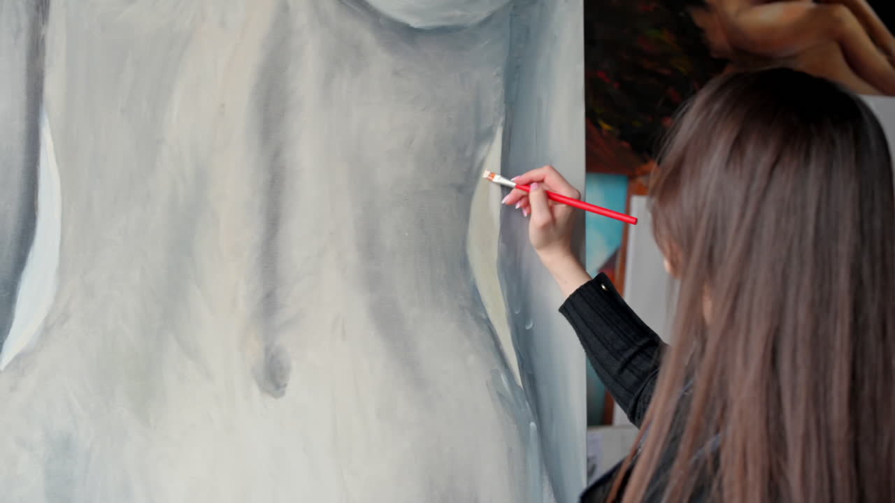 Donna che dipinge un corpo femminile su un'area di lavoro durante un workshop in una galleria d'arte