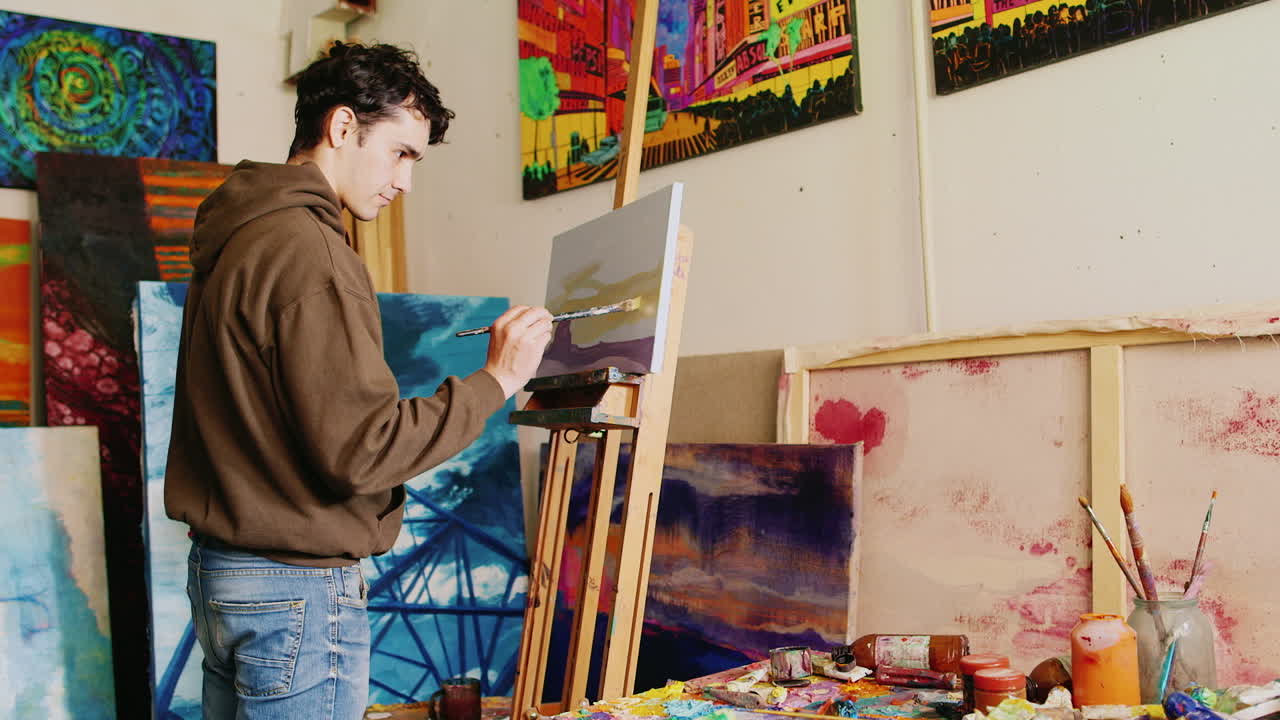 Trabajando en el estudio creativo del pintor. Joven artista mestiza pinta un cuadro.