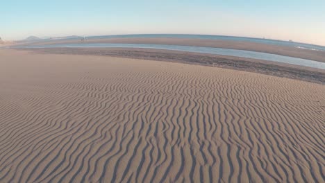 parallel lines in the sand weaving their way to the pacific ocean