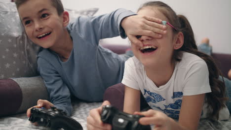 Kids-playing-video-games.-Brother-close-eyes-sister.-Children-have-fun-together