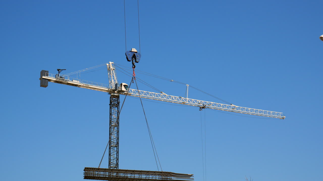 Construction Crane Lifting Rebar Against a Blue Sky