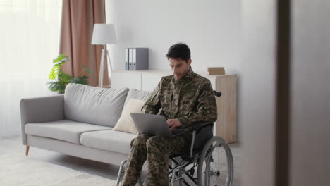 soldier in wheelchair working on laptop at home