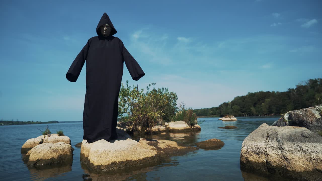 Eerie witch on river bank watches the camera