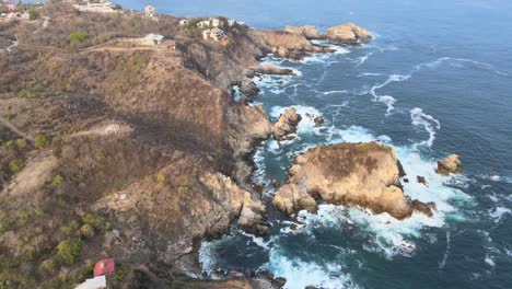 retroceda y vea los acantilados y el pequeño faro de puerto ángel en la costa rocosa de oaxaca