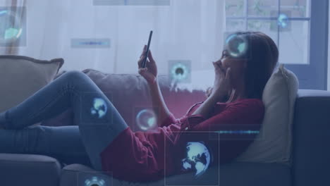 animation of data processing over biracial woman using smartphone on sofa