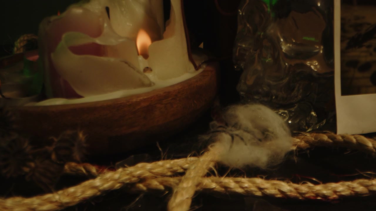 Concetto horror: Carrellata in avanti su un altare occulto con candele accese, vetri rotti e corde insanguinate.