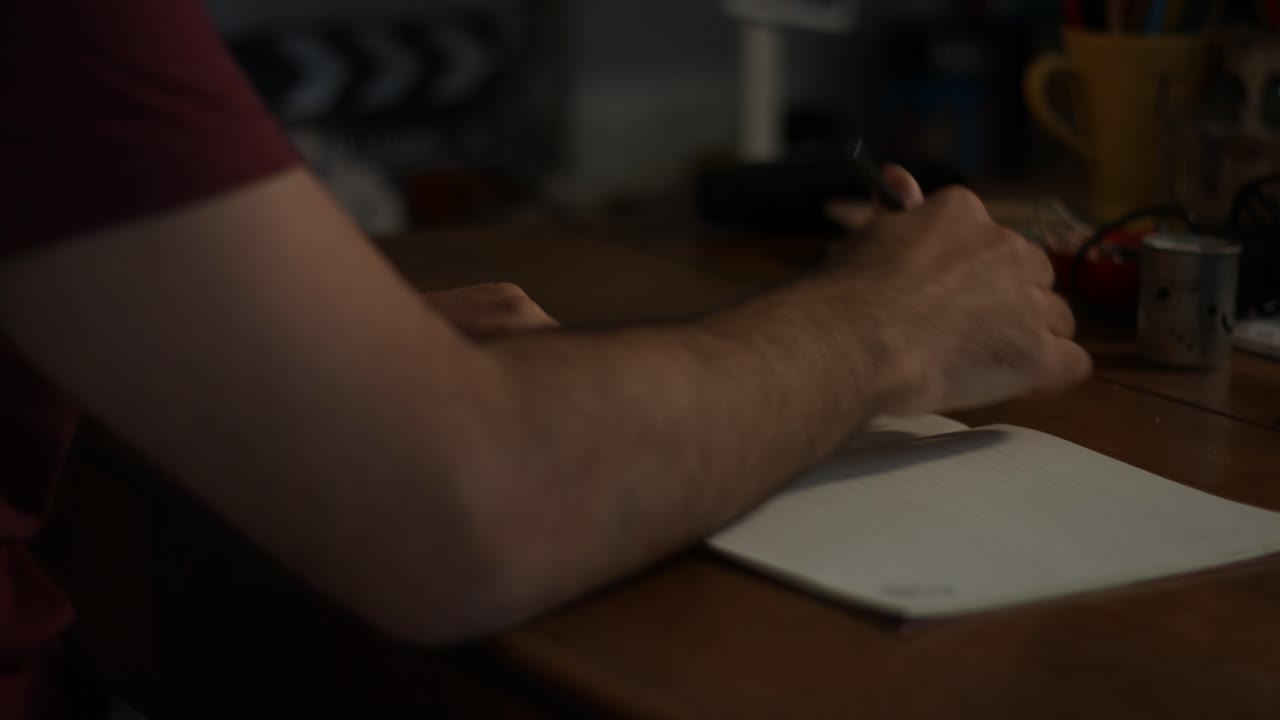 Close-Up of Person Writing in Notebook at Desk