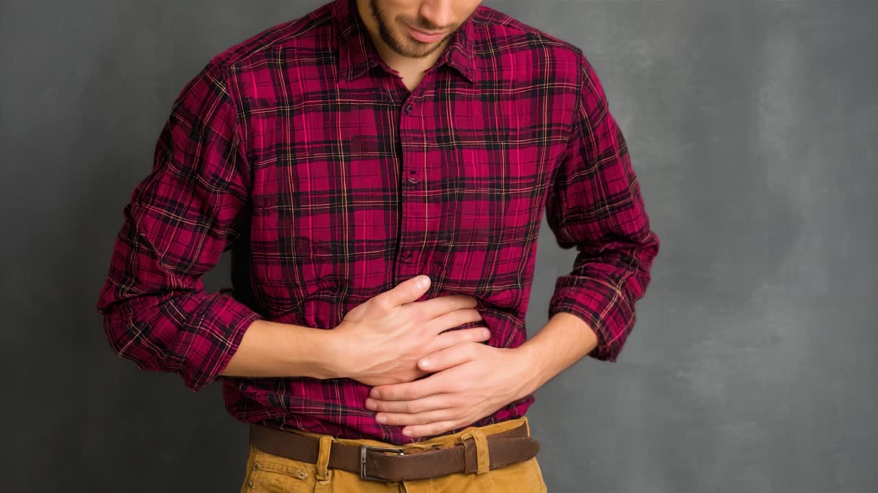 Un uomo che prova disagio, si tiene lo stomaco ed esprime segni di malessere in un ambiente interno ben illuminato, mostrando l'impatto dei problemi gastrici sulla vita quotidiana