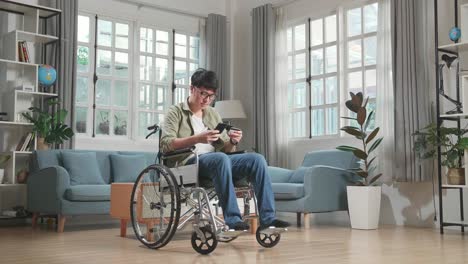 asian man sitting in a wheelchair while use mobile phone and credit card shopping online at home