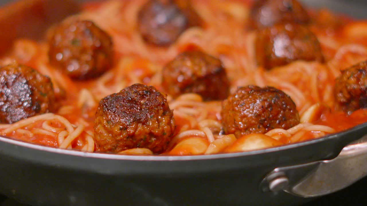 Overview of Delicious Italian Meatballs with Spaghetti Pasta in Rich Tomato Passata Sauce with Herbs with Wooden Spoon. Homemade Cooking Food Footage.