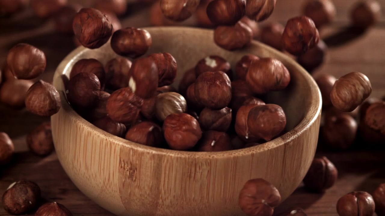 Nocciole che cadono al rallentatore in una ciotola di legno