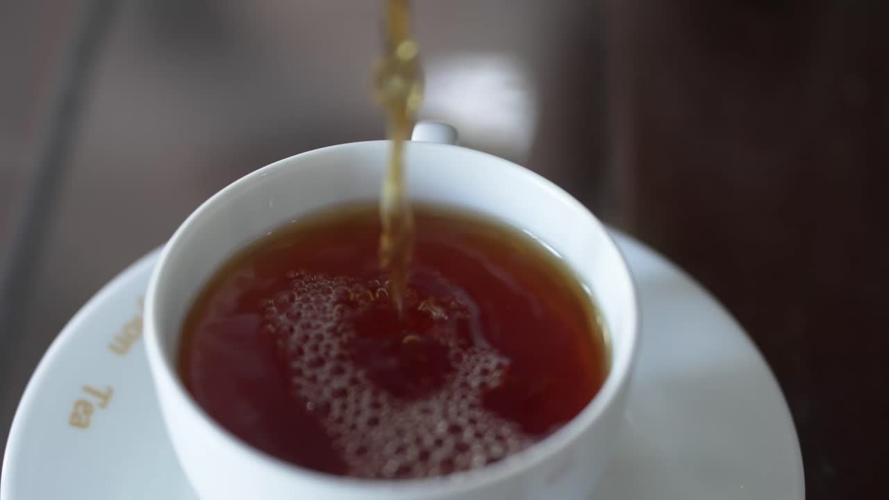 Primo piano del tè di Ceylon versato in una tazza in Sri Lanka, che evidenzia il colore intenso e il calore della bevanda.
