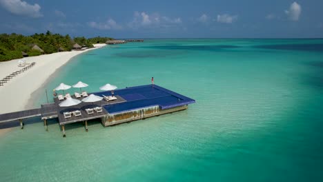 woman in red bathing suit standing at edge of overwater infinity pool at luxury maldives resort