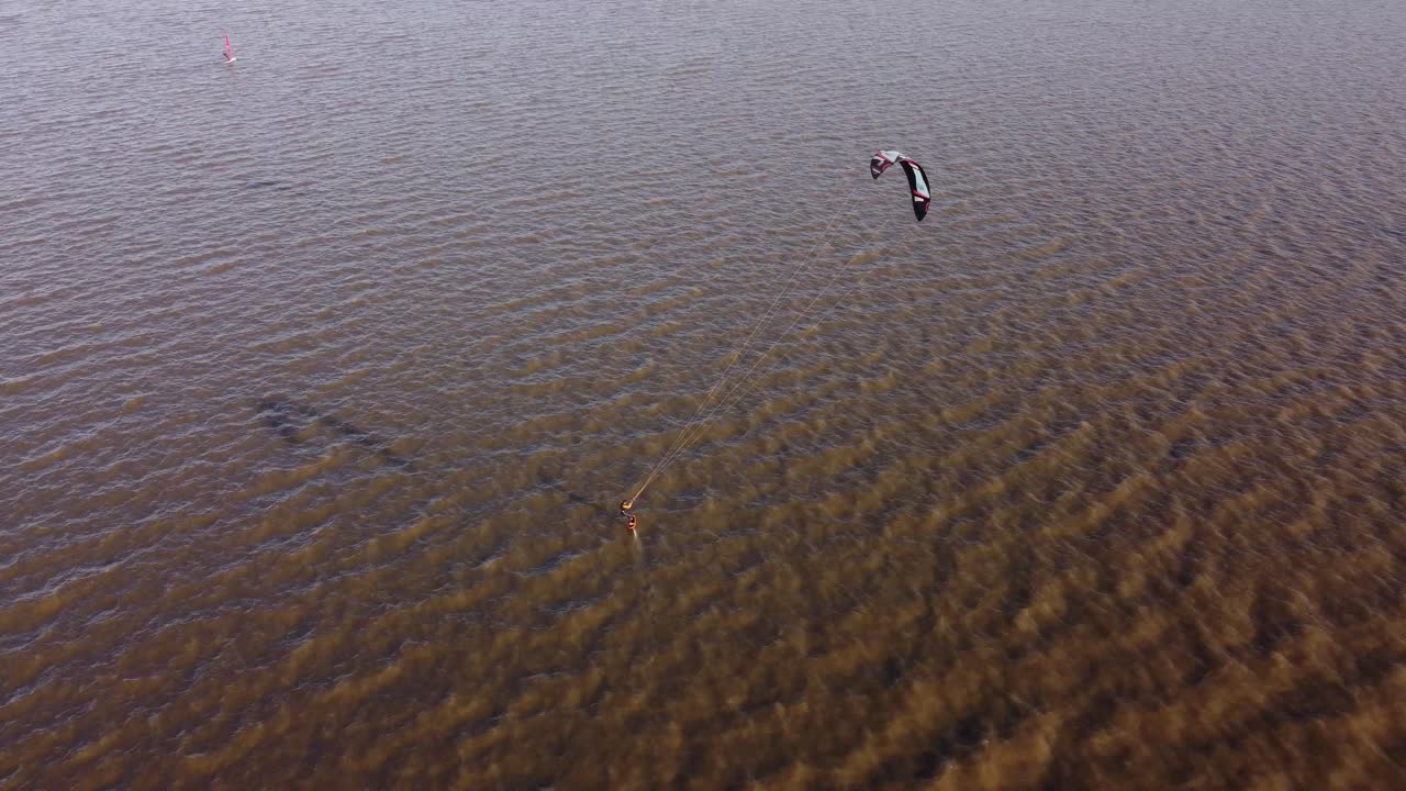 일몰 시간에 더러운 강에서 속도로 카이트서퍼 카이트 보딩의 공중 추적 샷