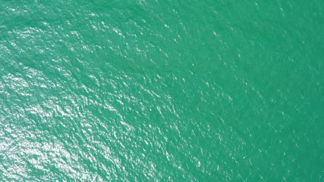 aerial top down view from high altitude of green sea water texture. the camera flies over the water, a view of the water surface. background of the water surface. 4k aerial view