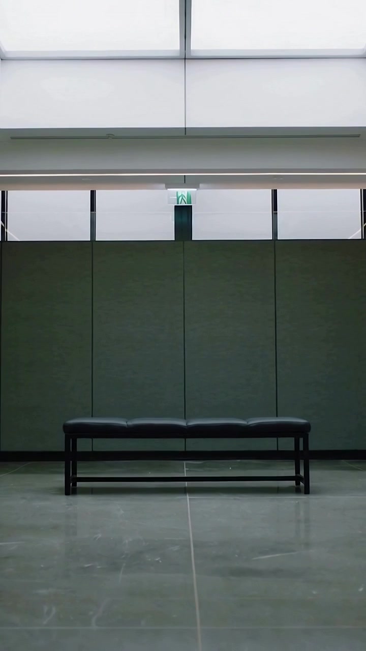 Vertical video: Tilting camera at start, revealing centered bench in hall with exit and skylight