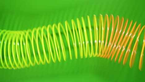 vintage retro abstract background. rainbow coloured spring moves across a green background in a wave like pattern. slinky toy. rainbow spiral spring motion wave a bright beautiful background.