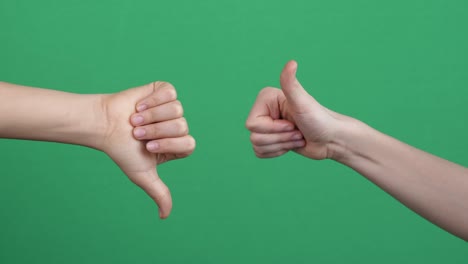 like dislike gestures. two hands showing different signs thumbs up and thumbs down gestures over green screen background