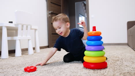 happy caucasian toddler building a toy pyramid cheerfully. cute smiling baby boy playing at home.