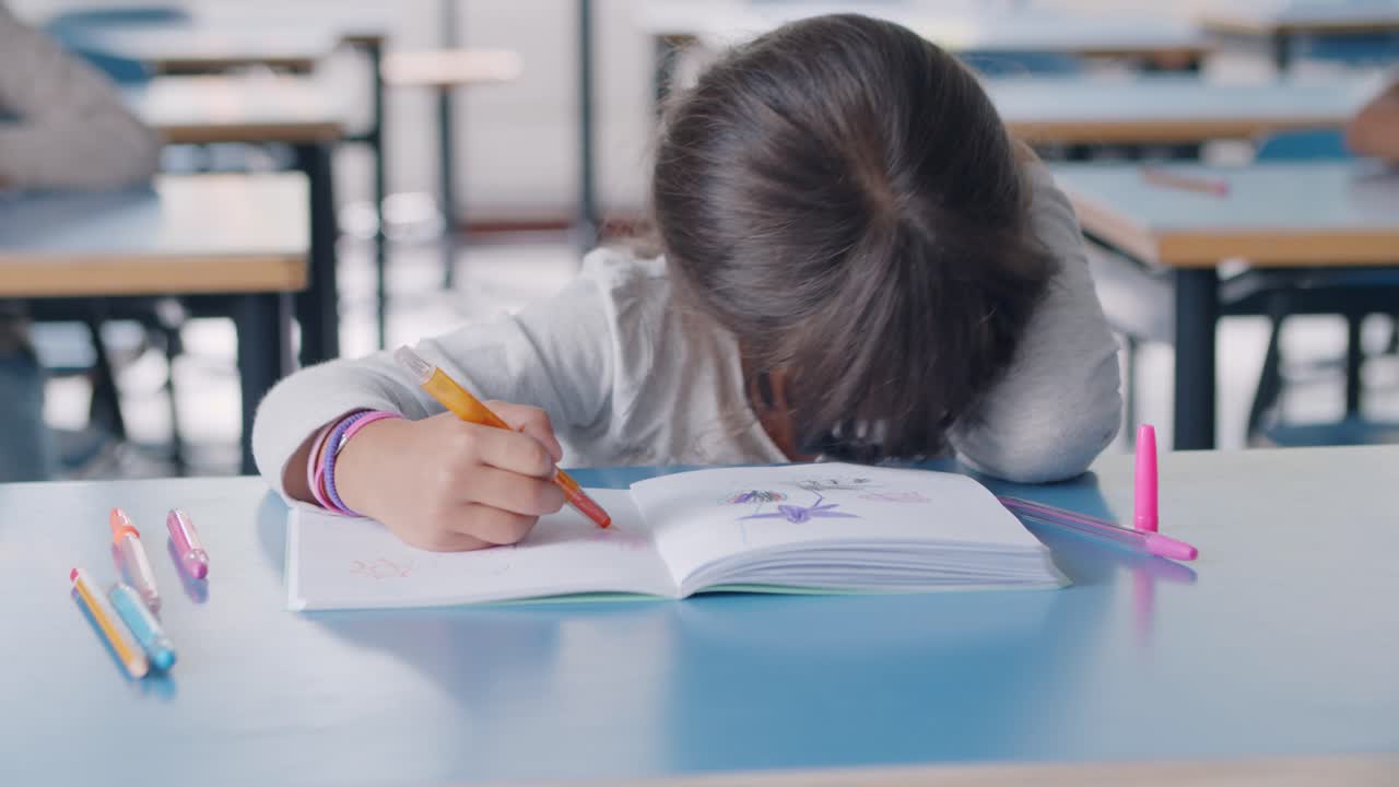 Bored tired Latin primary schoolgirl using colored marker