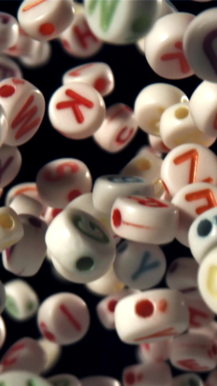 Colorful Alphabet Letter Beads Floating Upwards on Black Background