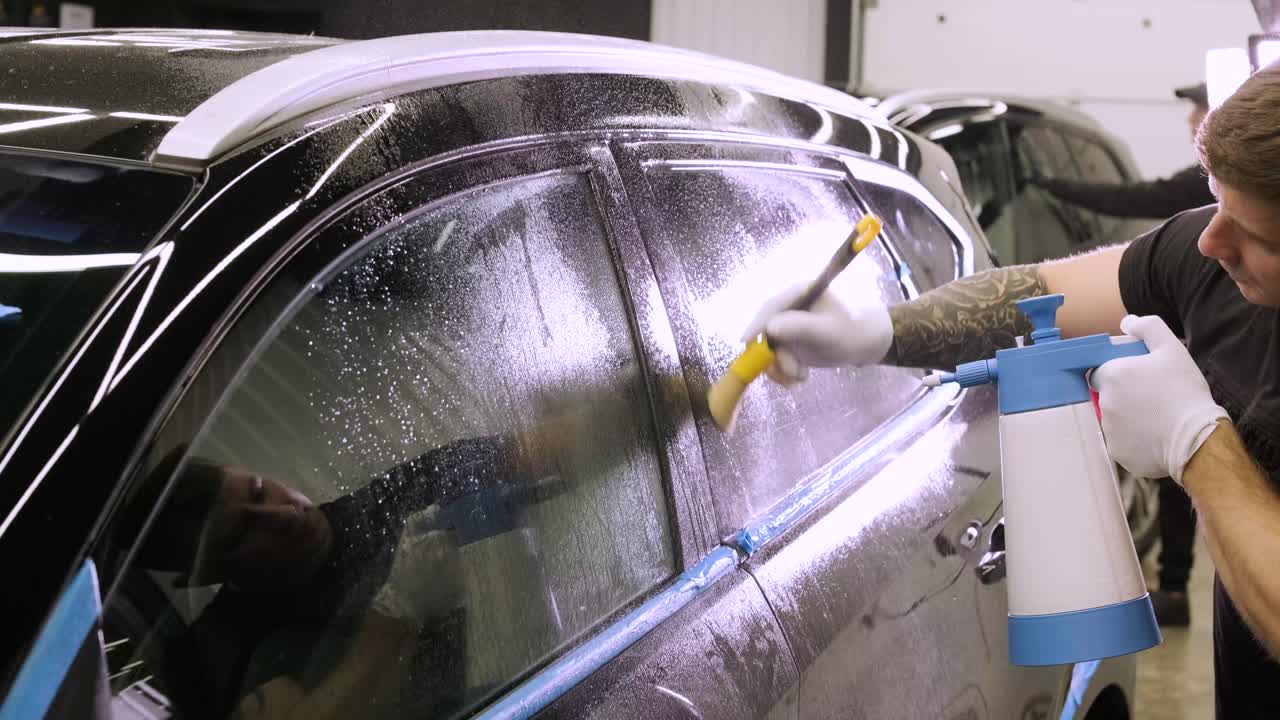 hombre que cubre el coche con cinta de poliuretano de vinilo. películas para el coche. pegatina película protectora en el coche