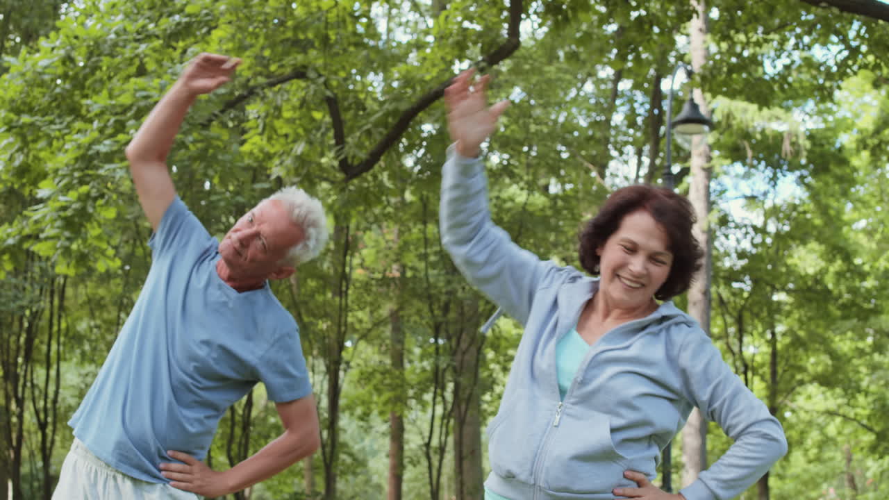 Coppia di anziani che fa stretching al parco