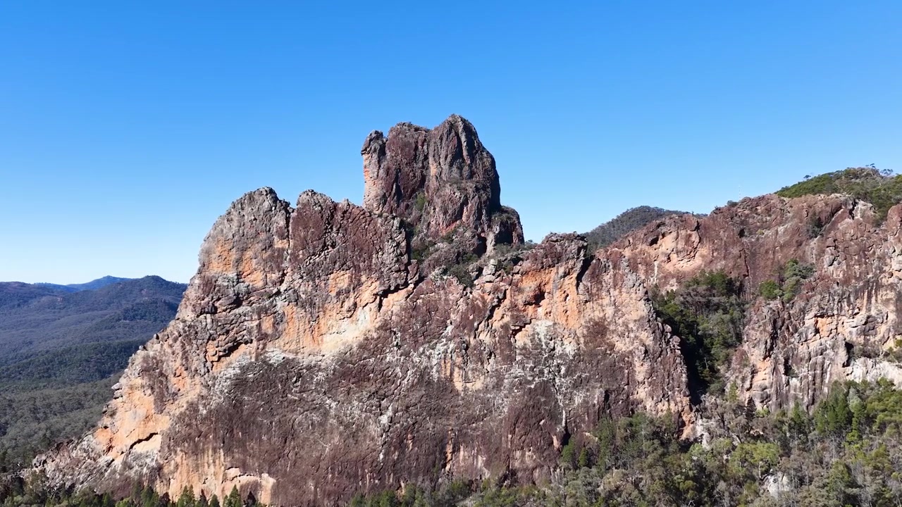 Weitwinkelaufnahme von alten vulkanischen Gesteinsformationen unter einem klaren blauen Himmel in Warrumbungle, Australien.