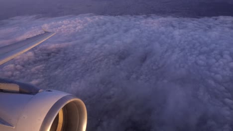 Static-aeroplane-window-view-of-the-engine-and-wing-of-a-jet-as-it-turns-left-and-tilts-the-wing-down-over-the-clouds-above-Paris