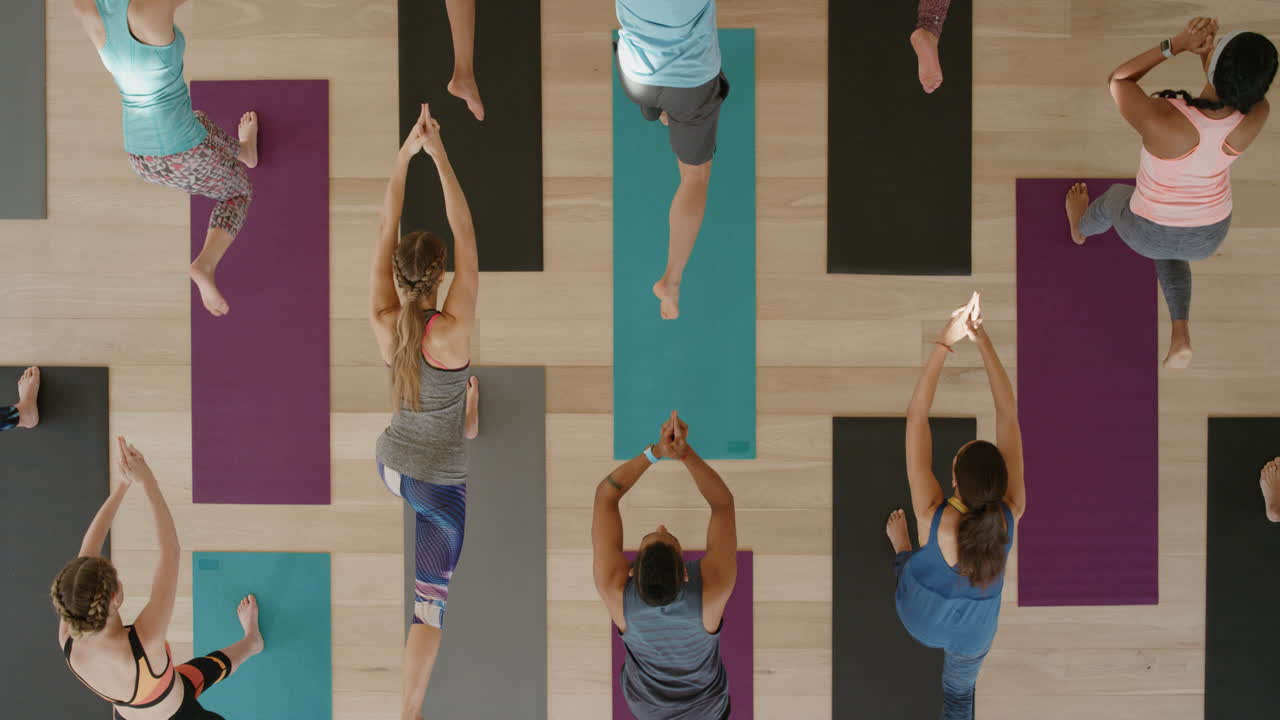 vista superior de la clase de yoga de jóvenes sanos practicando pose de guerrero estirándose disfrutando del estilo de vida físico haciendo ejercicio en el estudio