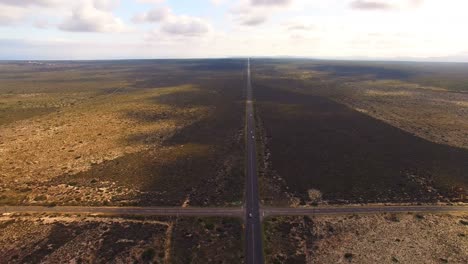 Aerial-view-of-a-dirt-road-winding-around-rural-field-