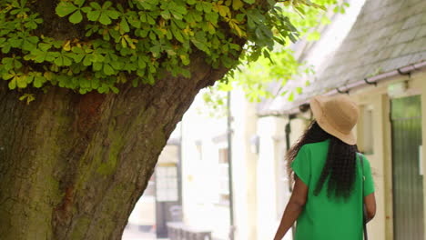 vista trasera de una turista femenina de vacaciones en oxford, reino unido, explorando la calle de la ciudad caminando a lo largo del pasaje del cordero y la bandera.