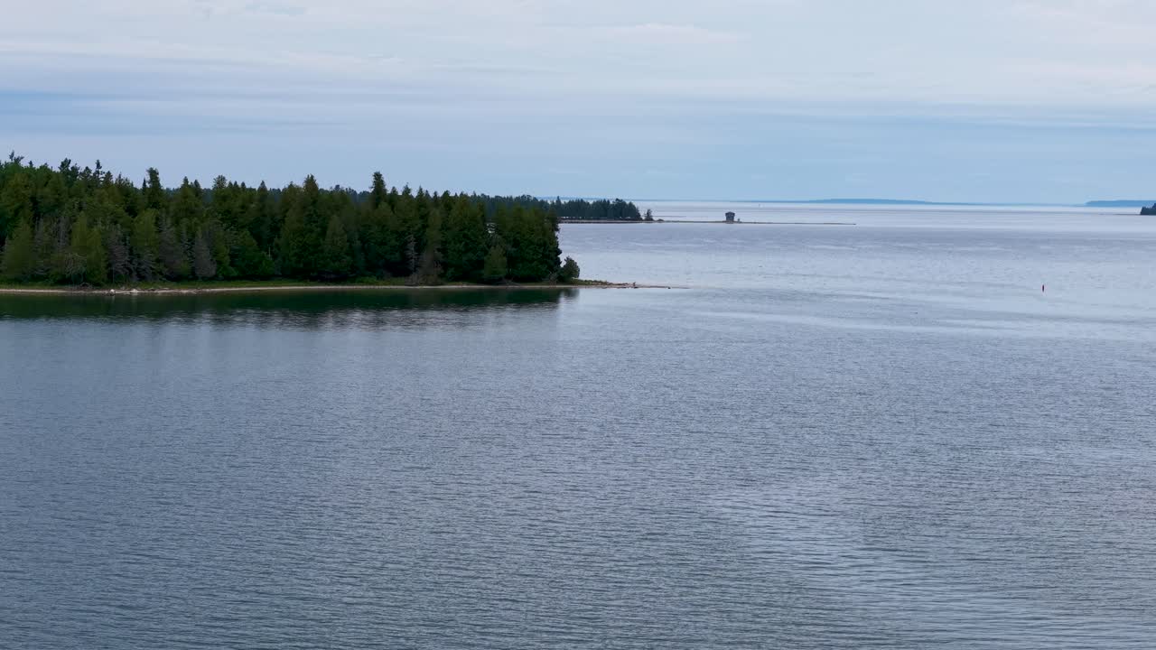 Aerial drone view of calm blue waters and forested shoreline in Michigan’s Les Cheneaux Islands, Upper Peninsula