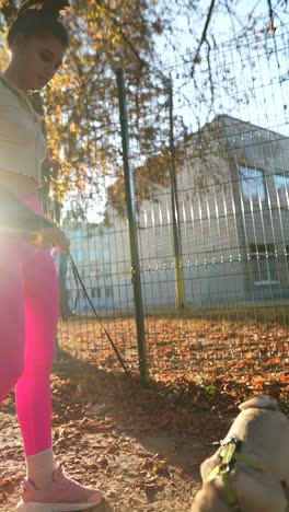 mujer paseando a su perro en un parque de otoño