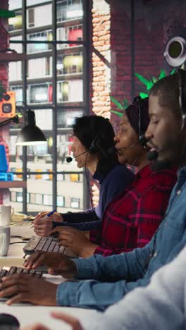 vertical video call center employees wearing headset assisting customers in office, close up
