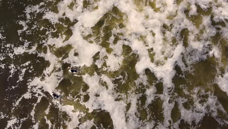 Toma-De-Cielo-De-Drones-De-Dos-Surfistas-Remando-En-Agua-De-Tormenta-Marrón-Olas-Del-Océano-Playa-De-Pájaros-área-De-Conservación-Del-Estado-De-Munmorah-Lagos-Playa-Costa-Central-Nsw-Australia-3840x2160-4k