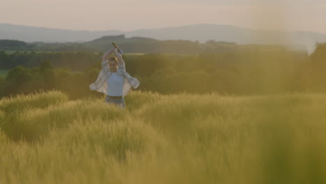 happy woman running through fields during sunset