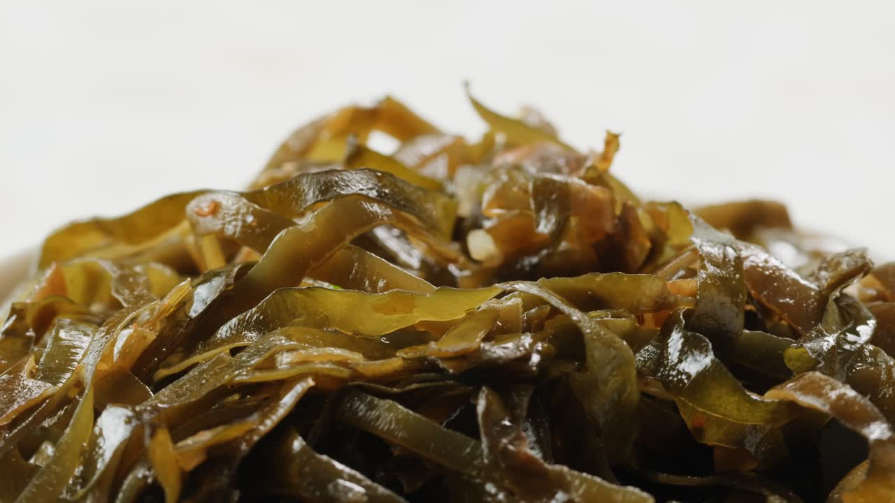 Japanese wakame sea weed laminaria chuka fermented food. Close-up on a detail of Hiyashi Wakame Chuka or seaweed salad or seaweed with sesame seeds on a plate. Top view. Seafood background.