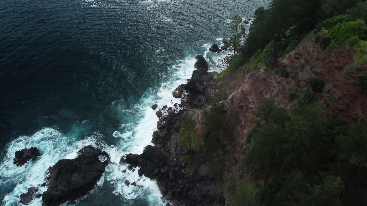 From cliffs above, tranquility on surface of rippling water and forest beyond
