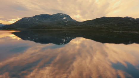 water reflections of gratifying sunset sky and norwegian alps in vavatnet, hydalen, hemsedal - wide shot