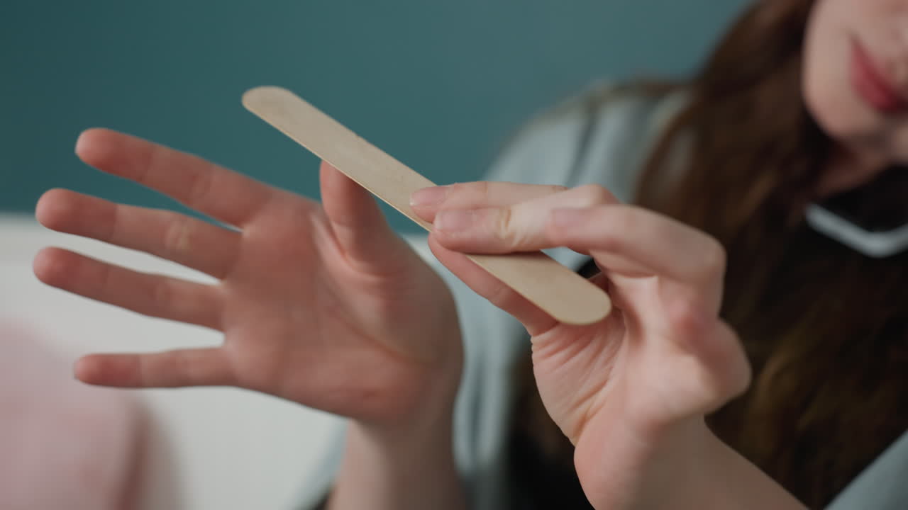 Woman manicures nails. Woman carefully caring for nails. Young woman diligently grooming her nails during routine care. Woman attentively tending to her nails as part of personal grooming routine