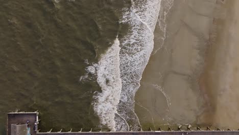 Drohne-Eines-Leeren-Strandes-Auf-Der-Insel-Tybee,-Der-über-Den-Pier-Fliegt,-Mit-Tosenden-Wellen-Und-Fliegenden-Vögeln