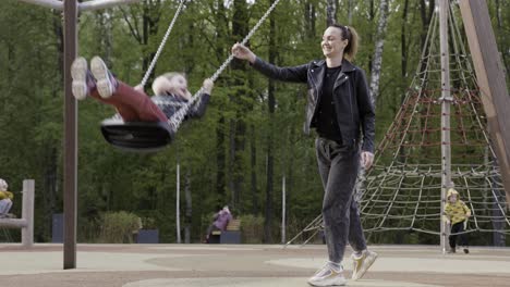 mother and daughter enjoying a swing set at the park