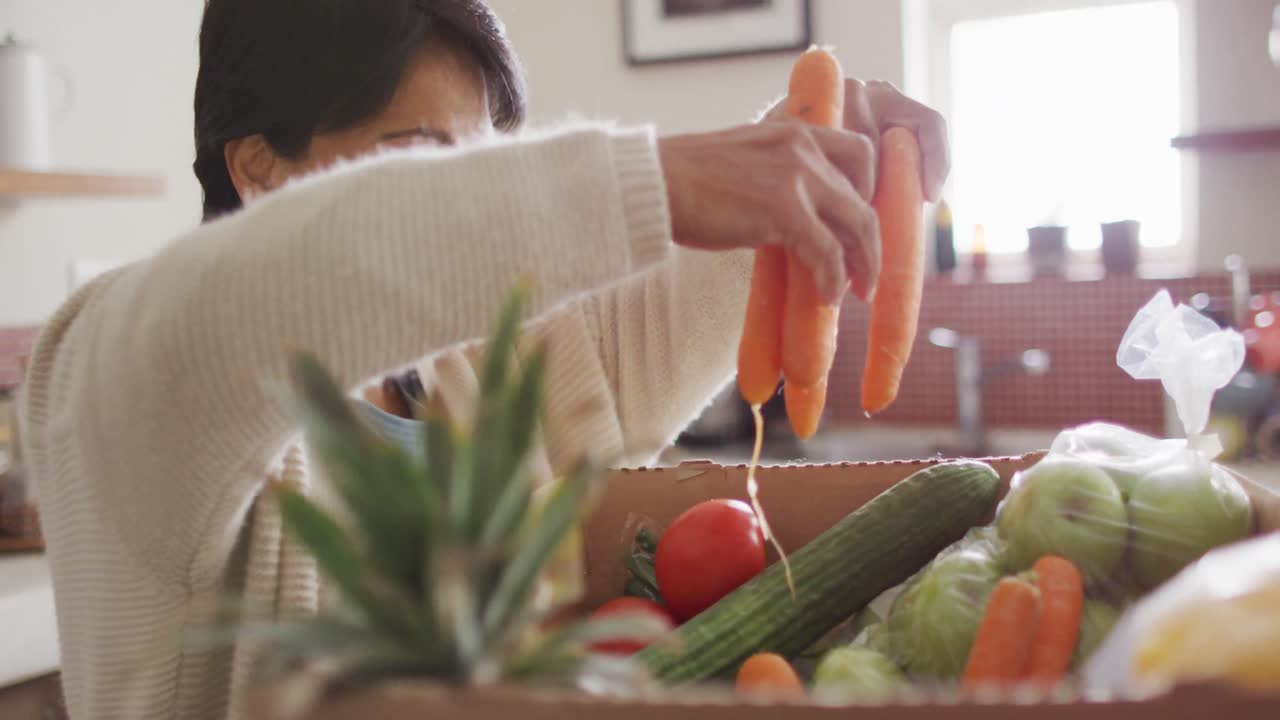 미소 짓는 고위 두 인종의 여성이 부 ⁇ 에서 혼자 채소를 잡고 있습니다.