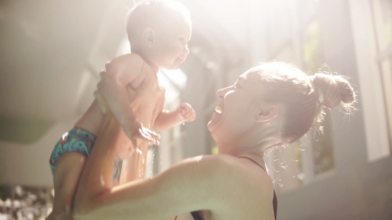 Free stock video - Happy young mom throws up baby in the pool