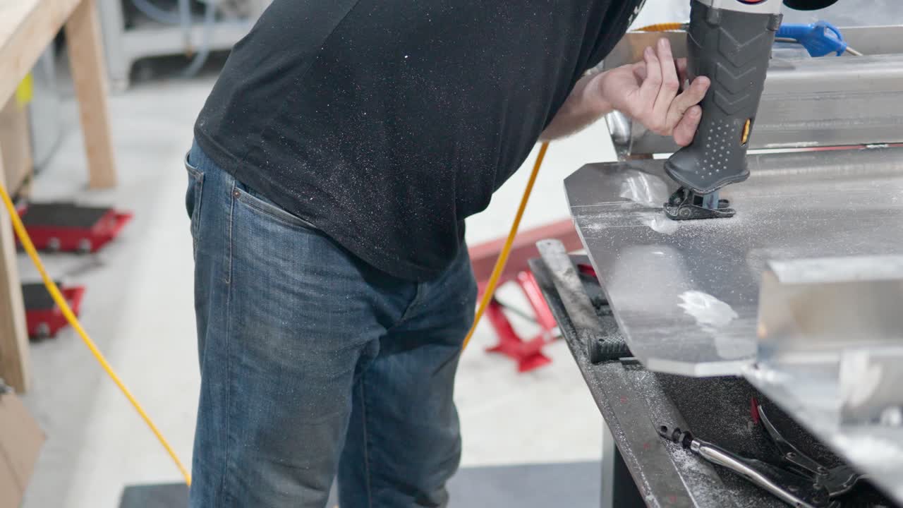 보트 생산 공장에서 전기 왕복 톱으로 금속을 절단하는 작업자 - 슬로우 모션