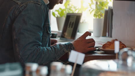 Junger-Mann-Liest-Geschäftsdokument-Im-Café-Und-Arbeitet-An-Einem-Projekt,-Trinkt-Kaffee-Und-Brainstorming-Ideen