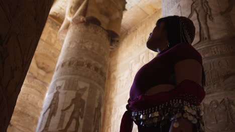 woman admiring ancient temple art in dendera, egypt, surrounded by carved columns