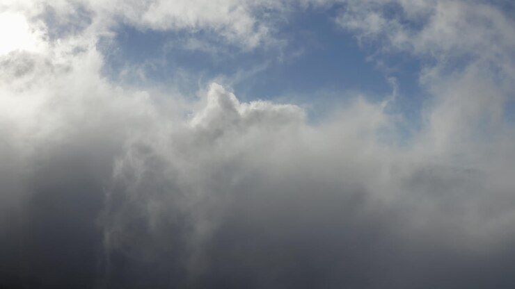 Blast of clouds moving towards the lens of a drone high in the air on a sunny day